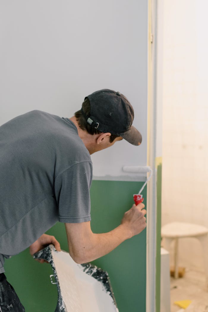 Mastering the First Impression: Your intriguing post title goes here A man painting walls with a roller during home renovation indoors.
