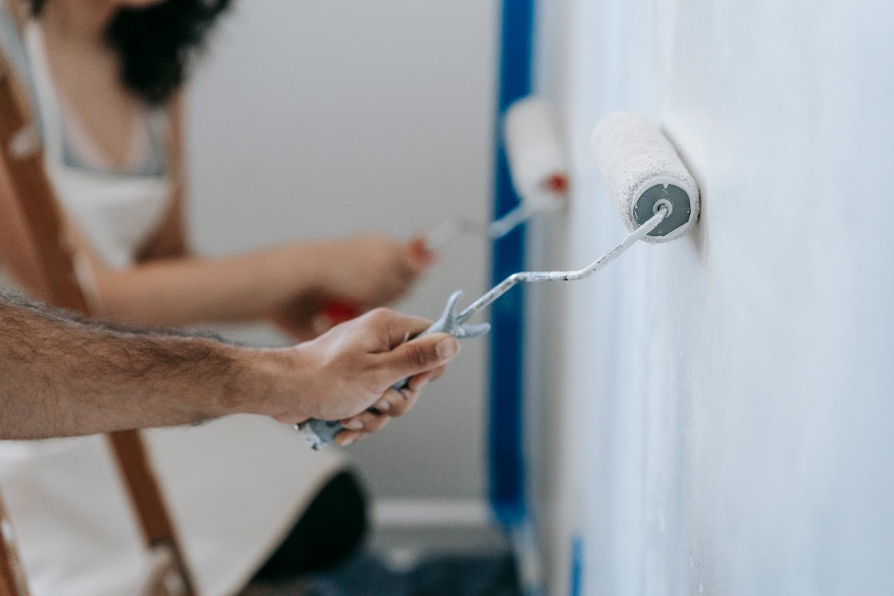 The Art of Drawing Readers In: Your attractive post title goes here Couple painting a wall with rollers, perfect for home improvement and renovation themes.